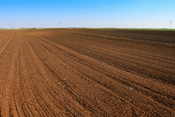 Fototapeta na wymiar Plowed field in spring time with blue sky