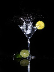 Fototapeta na wymiar ice splash in martini glass with lime on black background