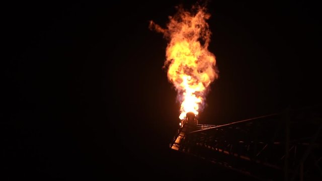 Oil and gas. Slow motion of gas flare from bottom burning at oil and gas platform at night.