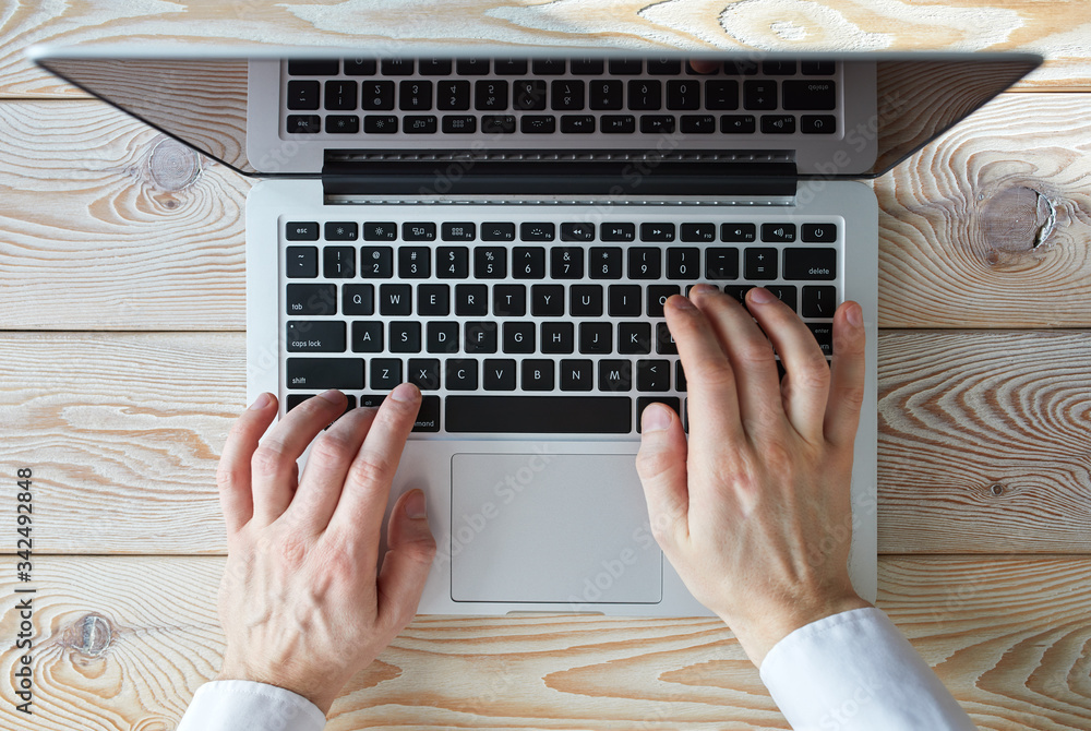 Poster top view of man's hands typing on laptop in sunny day. coworking or working at home concept image.