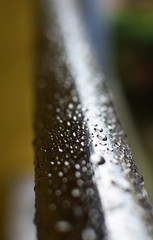 Raindrops on the chrome handrail. Rainy weather. Selective focus on the drops.