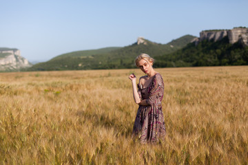 Naklejka na ściany i meble Portrait of a beautiful fashionable woman in a field harvesting