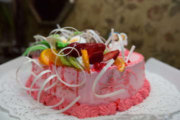 Beautiful pink wedding cake with dolls of the bride and groom on top of the cake
