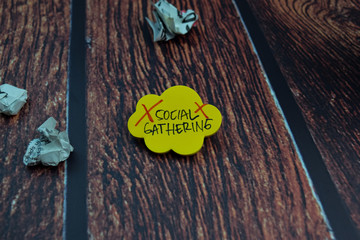Social Gathering write on a sticky note Isolated on wooden table background