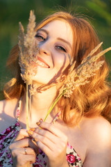 close up portrait of redhead attractive pretty young girl with yellow spica grass