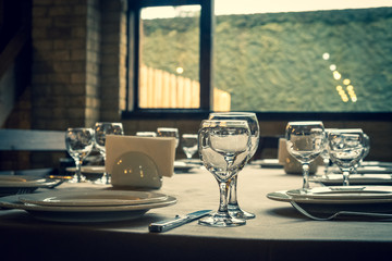 The served table in the restaurant. Clean dishes and appliances on the tablecloth in a cafe. Shiny transparent glasses. White plates. Prepared for the reception of guests. High service.