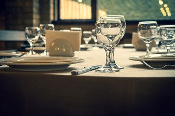 The served table in the restaurant. Clean dishes and appliances on the tablecloth in a cafe. Shiny transparent glasses. White plates. Prepared for the reception of guests. High service.