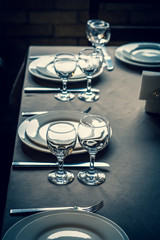 The served table in the restaurant. Clean dishes and appliances on the tablecloth in a cafe. Shiny transparent glasses. White plates. Prepared for the reception of guests. High service.