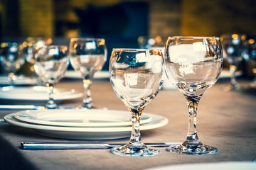 The served table in the restaurant. Clean dishes and appliances on the tablecloth in a cafe. Shiny transparent glasses. White plates. Prepared for the reception of guests. High service.