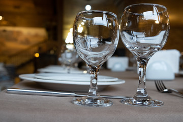 The served table in the restaurant. Clean dishes and appliances on the tablecloth in a cafe. Shiny transparent glasses. White plates. Prepared for the reception of guests. High service.
