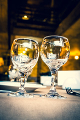 The served table in the restaurant. Clean dishes and appliances on the tablecloth in a cafe. Shiny transparent glasses. White plates. Prepared for the reception of guests. High service.