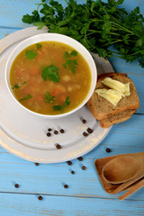tripe soup in a white bowl next to bread and butter