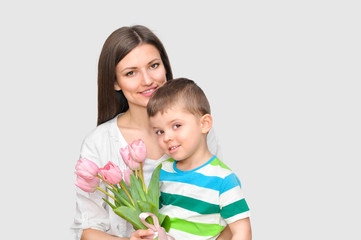 Little child son gives his mother a bouquet of delicate pink tulips. Mother's Day celebration.	