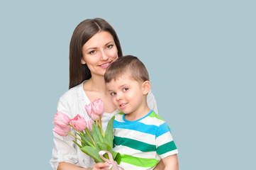 Little child son gives his mother a bouquet of delicate pink tulips. Mother's Day celebration.	