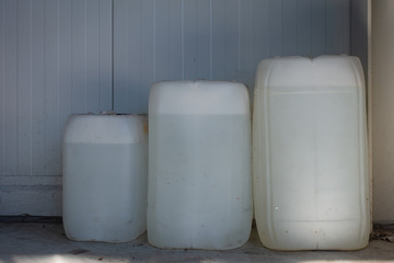 three filled white canisters of different sizes standing on a wall in a workshop