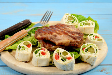 Sliced tortilla with vegetables next to fried grilled steak