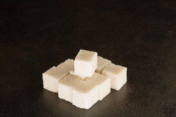 tas de morceaux de sucre de canne raffiné blanc sur un fond noir