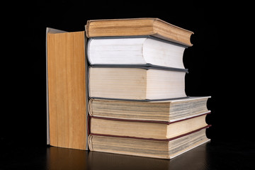 An open large book against the backdrop of a row of paper publications. Heap of old books and guides.