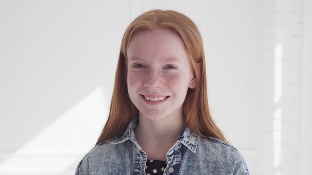 Cheerful smiling face of beautiful teen girl with freckles and red hair