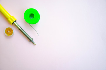 Soldering iron, tin, rosin on a pink background. Soldering iron in male hands. Macro. Repair of electrical equipment, radio engineering. Solder wires, contacts.  Copy Space