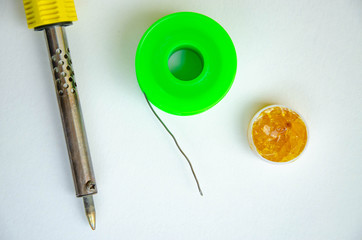 Soldering iron, tin, rosin on a white background. Soldering iron in male hands. Macro. Repair of...