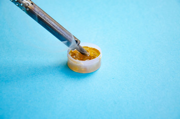Soldering iron, tin, rosin on a blue background. Soldering iron in male hands. Macro. Repair of...