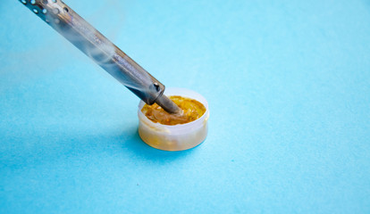 Soldering iron, tin, rosin on a blue background. Soldering iron in male hands. Macro. Repair of electrical equipment, radio engineering. Solder wires, contacts.  Copy Space
