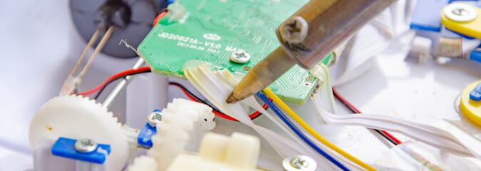 Soldering iron, tin, rosin. Soldering iron in male hands. Macro. Repair of electrical equipment, radio engineering. Solder wires, contacts.  Copy Space