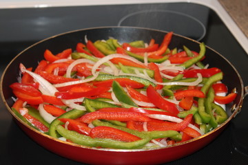 Peppers and onions frying in a pan