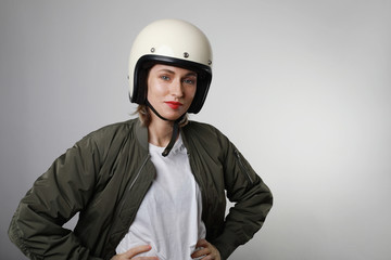 Portrait of young sexy woman wearing a motorcycle white helmet posing over isolated white background.