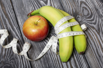 Bananas, measuring tape and apple. On brushed pine boards. Symbol of World No Diet Day.