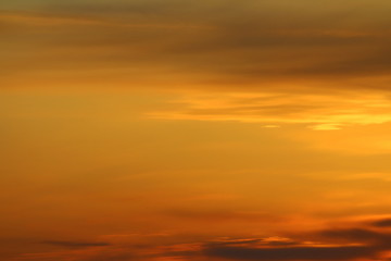 Naklejka na ściany i meble Sun below the horizon and clouds in the fiery dramatic orange sky at sunset or dawn backlit by the sun. Place for text and design.