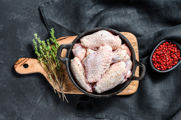 Raw chicken wings with spices and herbs in a pan. Black background. Top view