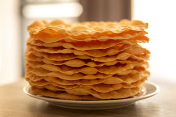 baked brown round cake cakes lie neatly flat on a white plate on a gray table. Cake without cream. The cake is called Napoleon.