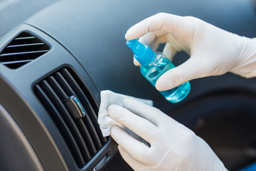 Professional worker using disinfectant and wet wipe to clean car interior.