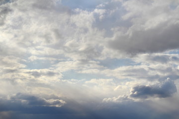 Fototapeta premium Clouds in the blue sky at sunset or dawn backlit by the sun. Place for text and design.