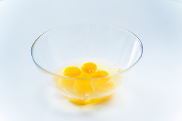 bright broken eggs in a glass plate on a white table