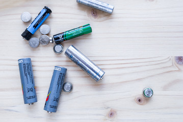 many batteries on wooden background top view