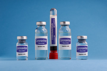 Corona virus vaccine for injection in sealed vials. Vaccine injection in sealed bottles and medical disposable plastic syringe against a blue background.