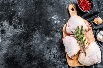 Raw chicken thigh, organic poultry meat. Black background. Top view. Copy space