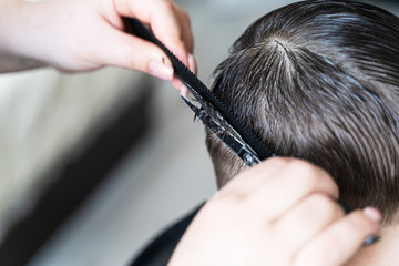 the boy is getting a haircut. scissors comb Barber