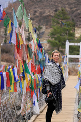Woman on a hanging bridge with prayer flags