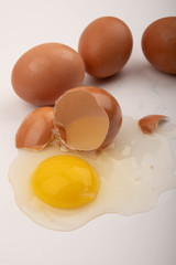 A broken chicken egg and scattered eggs on a white background. Close up.