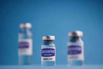 Corona virus vaccine for injection in sealed vials. Vaccine injection in sealed bottles and medical disposable plastic syringe against a blue background.