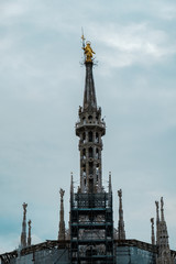 Obraz premium Pinnacle with the golden sculpture of Madonnina, Santa Maria, on top of the roof of Milan Cathedral