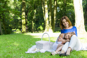 Beautiful little girl in a park on a picnic with straw basket and hat. Spring sunny concept. Happy mothers day. Happy loving family. Mother and daughter. Lifestyle concept.
