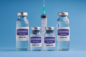Corona virus vaccine for injection in sealed vials. Vaccine injection in sealed bottles and medical disposable plastic syringe against a blue background.