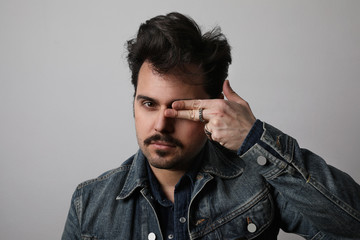 Headshot of serious stylish man looks straight with confident expression, wears denim jacket, isolated.