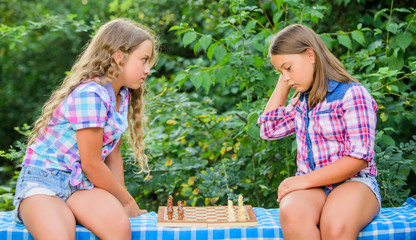 Fototapeta premium Think better. Little girls play chess. Sisters playing chess. Smart children. Early childhood development. Intellectual game. Children play chess outdoors nature background. Sport and hobby concept