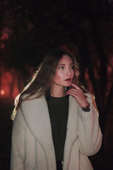 Night portrait of a young woman in a white fur coat